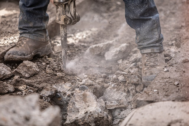 Worker breaking rocks with power tools